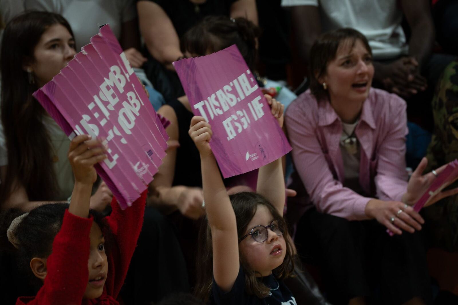 Enfants brandissant des pancartes roses « Tous ensemble Let's go NBF »