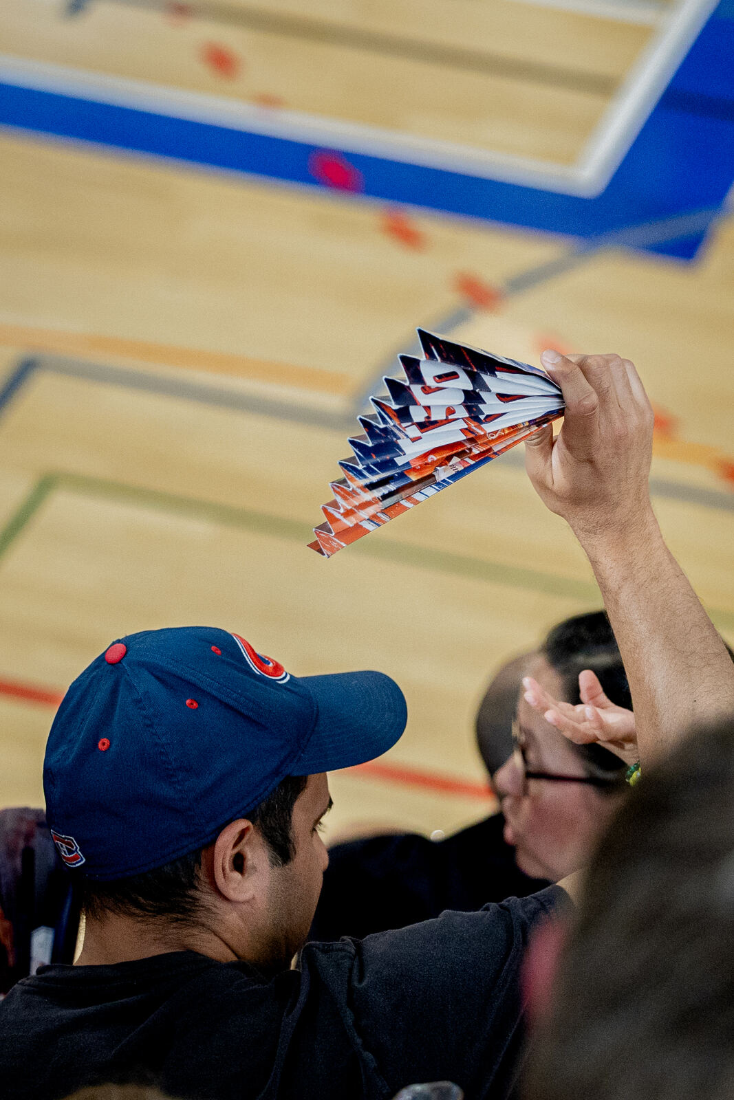 Supporter casquette BBC Nyon brandissant un éventail Let's Go Nyon au-dessus du parquet